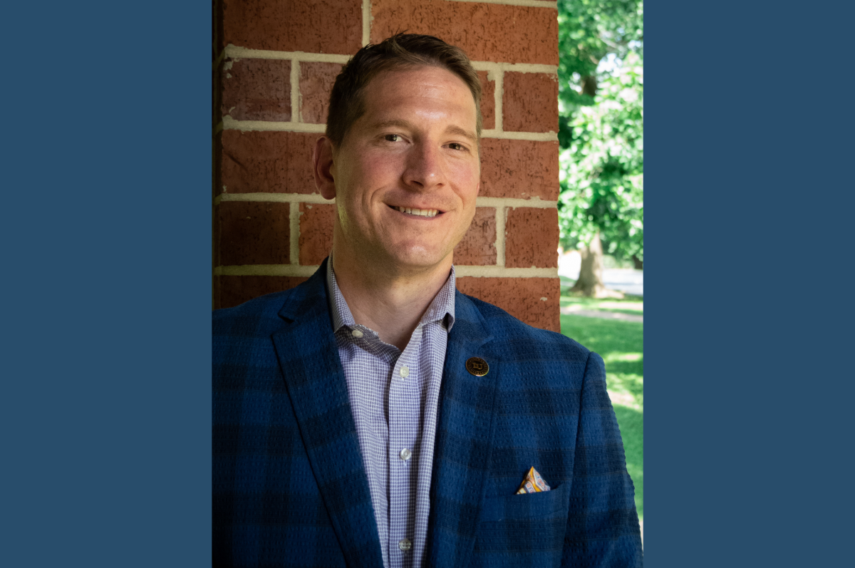 Man in blue jacket standing in front of brick wall